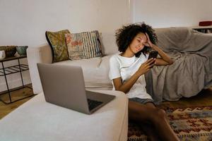 jovem negra usando um telefone celular enquanto está sentada no chão foto