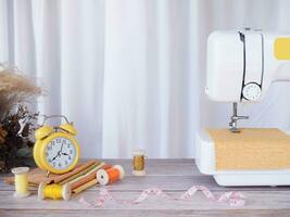 de costura máquina trabalhando com amarelo tecido, de costura acessórios em a mesa, ponto Novo roupas. foto