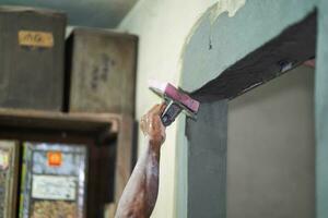 fechar-se mãos do construtor segurando argamassa panela e esponja reboco paredes com cimento dentro construção local. usando uma esponja para gesso em a parede ajuda para suave a gesso área. Mais lindo foto