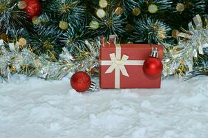 Natal arranjo com Natal árvore galhos, vermelho ouropel, vermelho presente e prata ouropel foto