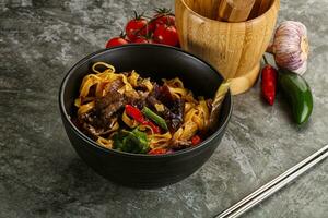 ásia wok com macarrão, legumes e carne foto