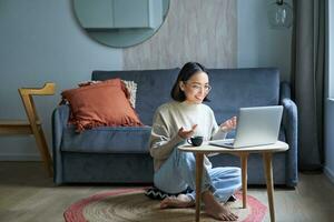 retrato do jovem trabalhando mulher, coreano menina estudando em controlo remoto on-line, falando para computador portátil, vídeo bater papo, tem conversação através da computador inscrição foto