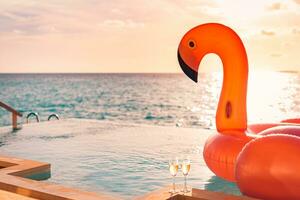 luxo infinidade natação piscina. pôr do sol feriado viagem período de férias fundo com engraçado flamingo brinquedo flutuador cabeçalho a champanhe óculos Como romântico casal fundo, exótico amor romance destino. foto