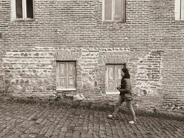 ásia mulher quem é fotógrafo caminhando dentro velho cidade. Preto e branco cor foto