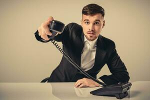 retrato do atraente homem de negocios segurando Telefone dentro dele mão foto