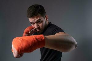 jovem lutador realizando esquerda espetar com mão embrulhado dentro boxe fita foto