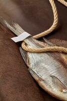 Ar seco barata rabo com papel rótulo e grosseiro corda em Castanho couro fundo foto