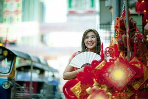 Mulher asiática vestindo roupas tradicionais chinesas com rosto sorridente de fã de bambu chinês em yaowarat street china cidade de bangkok, tailândia foto