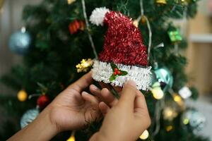 alegre Natal 2024 conceito ásia mulheres decorar a Natal árvore com colorida Natal bolas. foto