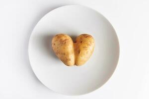 coração em forma batatas em uma branco placa. dia dos namorados dia conceito. feio Comida. foto