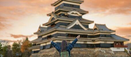 mulher turista visitando dentro matsumoto, feliz viajante passeios turísticos Matsumoto castelo ou Corvo castelo. ponto de referência e popular para turistas atração dentro matsumoto, Nagano, Japão. viagem e período de férias conceito foto