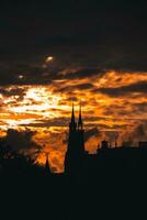 tormentoso e dramático pôr do sol e silhuetas do a catedral pináculo dentro Amsterdã, Países Baixos foto