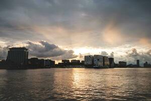 tempestade nuvens durante pôr do sol viagem através a cidade do amsterdam e dar uma dramático atmosfera. holandês estilo de vida e moderno cidade cenário foto