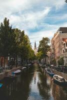 pôr do sol ilumina uma água canal e adjacente edifícios dentro a capital cidade do Amsterdã, a Holanda. Veneza do a norte foto