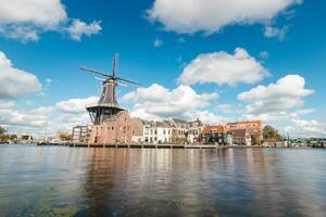 Visão do haarlem cidade Centro com a iluminado histórico moinho e edifícios. típica holandês arquitetura. explorando Holanda foto
