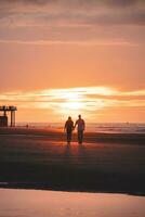 romântico andar do uma jovem casal em a praias do ostende dentro ocidental Bélgica às pôr do sol. amor e devoção. reflexão dentro uma piscina do água foto