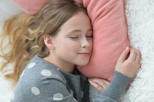 doce pequeno menina dormindo dentro uma cama foto