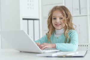 fofa e feliz pequeno menina crianças usando computador portátil computador foto