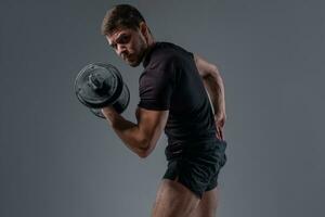 muscular jovem fisiculturista fazendo bíceps ondulação com haltere foto