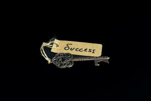 chave para sucesso conceito - velho chave com sucesso tag isolado em Preto fundo foto