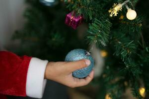 alegre Natal 2024 conceito ásia Garoto decora Natal árvore com colorida Natal bolas. foto