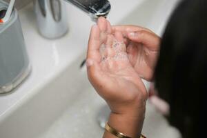 criança lavando as mãos com sabão foto