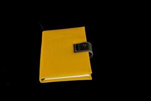 uma amarelo caderno cobrir em Preto fundo foto
