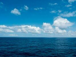 uma azul oceano com nuvens dentro a céu foto