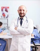 retrato do jovem especialista médico olhando às Câmera dentro hospital conferência sala. amigáveis médico praticante dentro clínica encontro sala, manto, especialista. foto