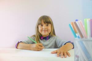 uma fofa branco menina é sentado às a mesa e fazendo trabalho de casa. cópia de espaço. foto