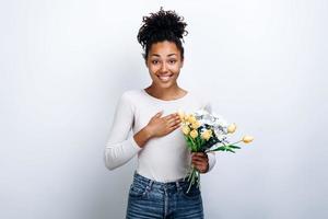 garota surpresa segurando um buquê de lindas flores nas mãos sobre um fundo de parede branca foto