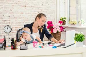 empresária mãe mulher com uma filha trabalhando às a computador portátil foto