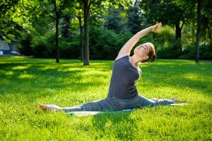 jovem mulher fazendo ioga exercícios dentro a verão cidade parque. foto