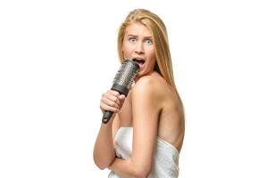 bonita mulher dentro toalha cantando usando pente foto