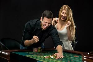 jovem casal a comemorar ganhar às roleta mesa dentro casino. foto