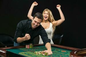 jovem casal a comemorar ganhar às roleta mesa dentro casino. foto