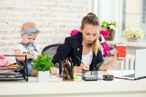 mãe e empresária trabalhando com computador portátil computador às casa e jogando com dela bebê garota. foto