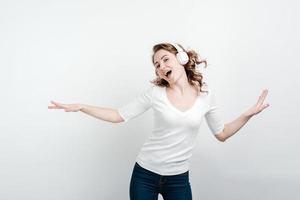 mulher feliz dançando com fones de ouvido sem fio cantando no estúdio foto