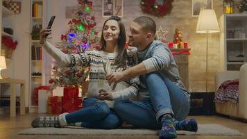 adorável casal em Natal dia bebendo champanhe falando uma selfie com Smartphone. foto