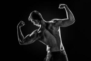 traseiro Visão do muscular jovem homem mostrando voltar, bíceps músculos foto