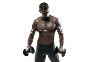 Atlético homem mostrando muscular corpo e fazendo exercícios com halteres foto