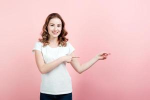 uma garota sorridente em uma camiseta branca está apontando a mão na direção. copie o espaço.