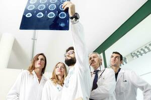 grupo do médicos examinando a raio X dentro hospital foto