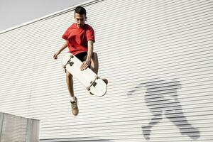 jovem skatista saltos acima com dele borda dentro frente do uma metal fundo foto