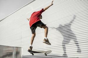 jovem skatista saltos acima com dele borda dentro frente do uma metal fundo foto