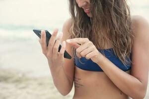 menina com telefone em a de praia foto