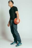 bonito jovem sorridente homem carregando uma basquetebol bola foto