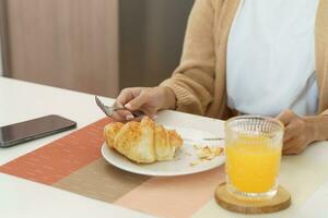 feliz mulher tendo café da manhã crocantes croissants foto