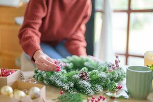 mulher fazer visco guirlanda Natal guirlanda decoração com mão fez faça você mesmo inverno vegetação florista mãos fazer Natal guirlanda lindo visco. foto