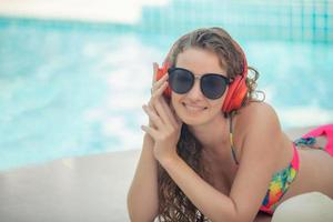 as mulheres usam biquínis, leem livros e ouvem música na piscina recreativa de verão. foto